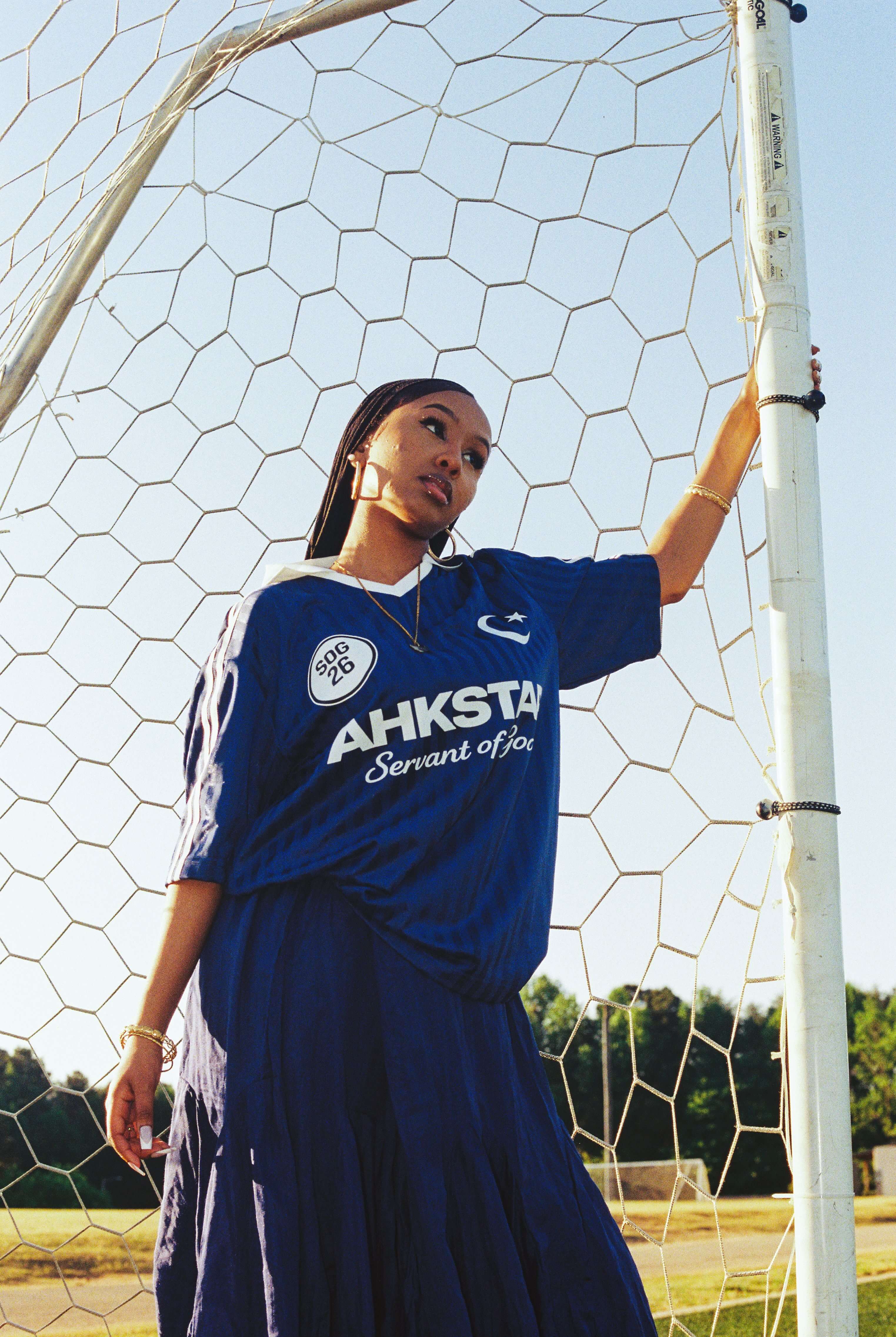 Model wearing Ahkstar's custom football-inspired jersey at a soccer field