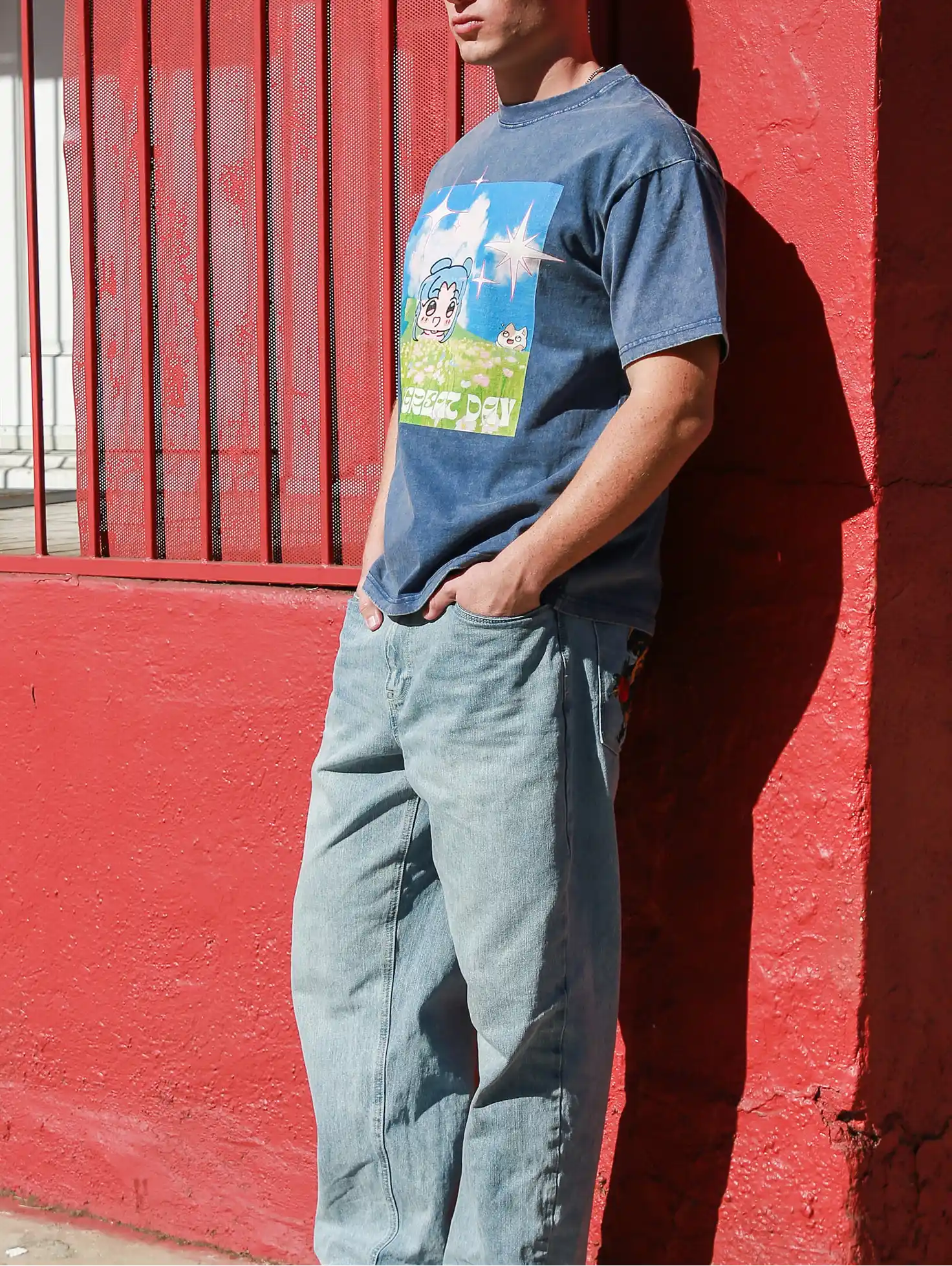The man, wearing a custom T-shirt with tapstitch, leaned against a red wall.