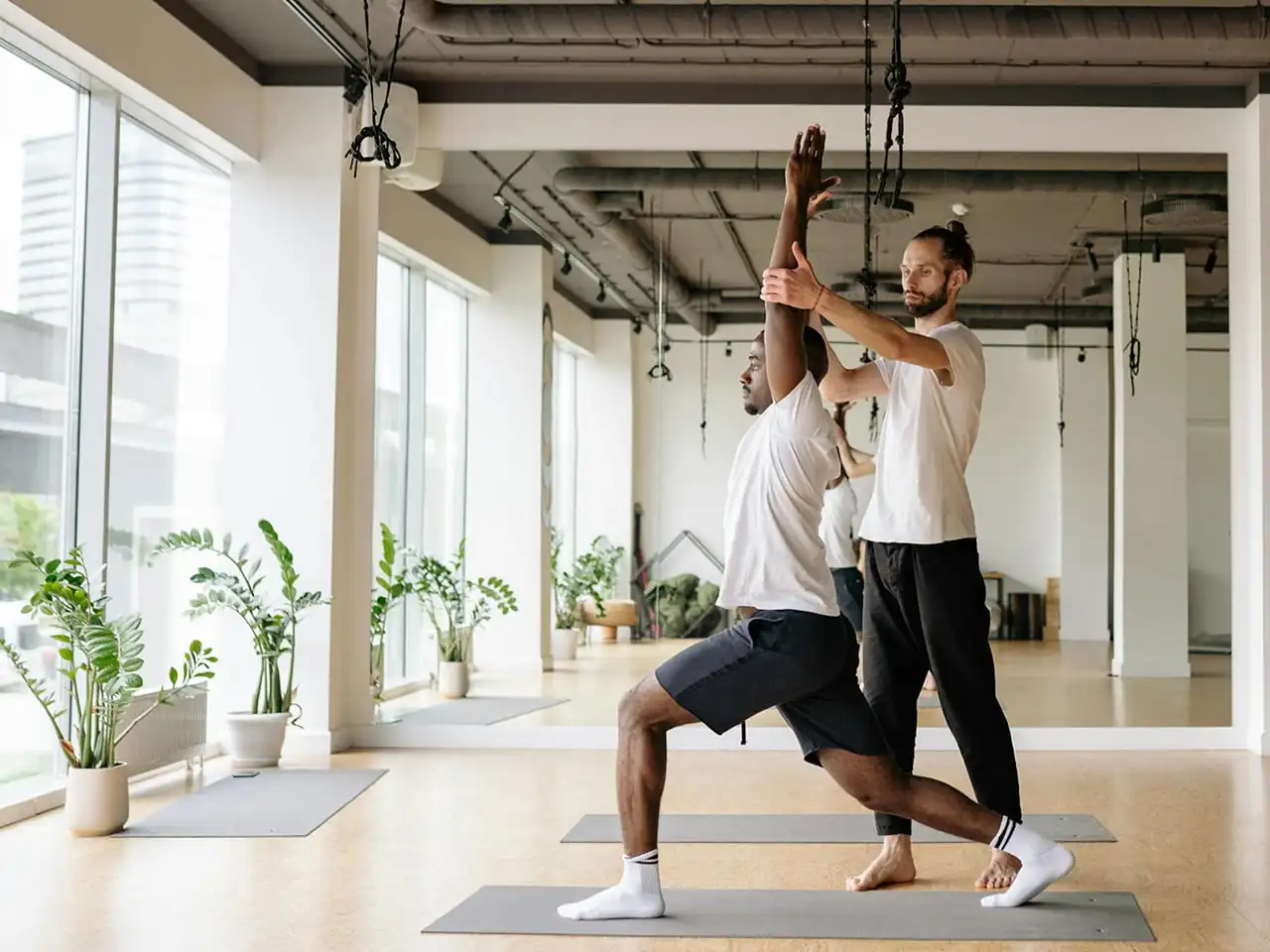 Two men in sports clothes are doing yoga.