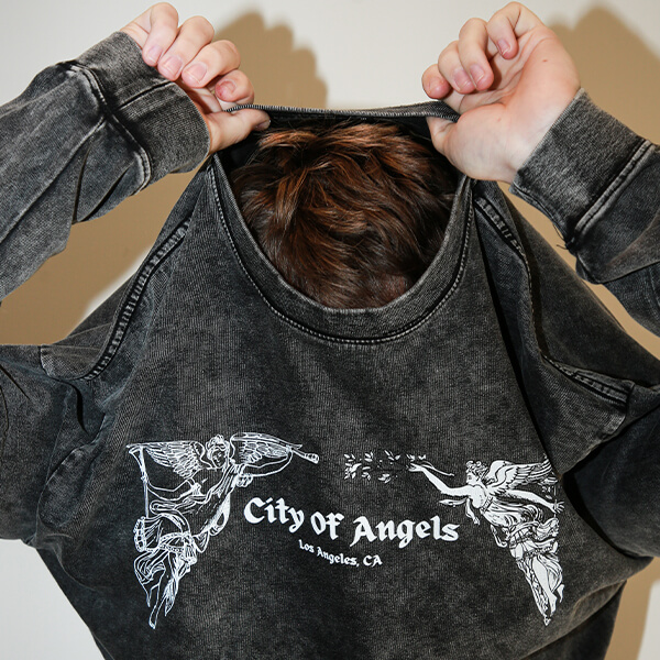 Person holding up vintage washed black t-shirt with graphic print design