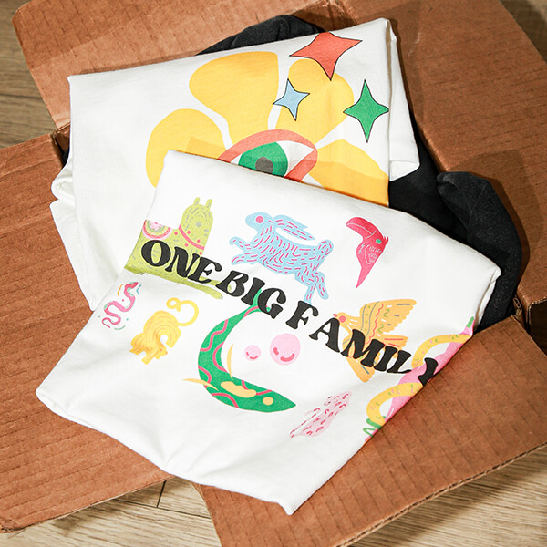 Folded custom printed t-shirts with colorful One Big Family graphic design in packaging box